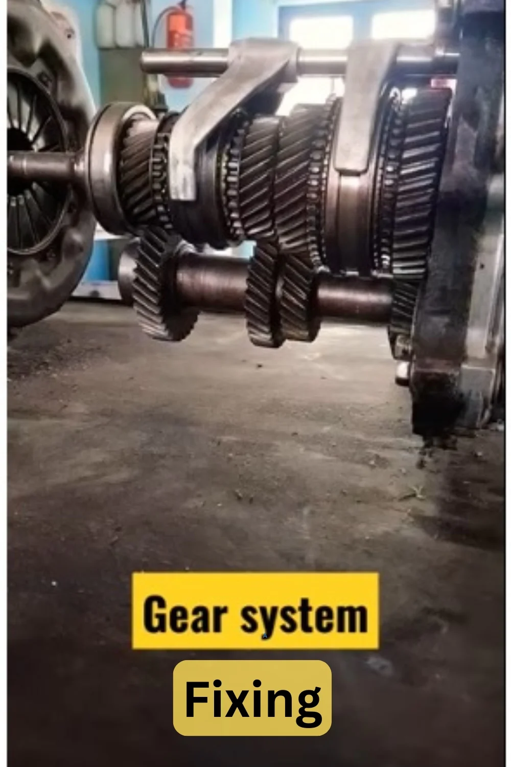 A disassembled gear system in a workshop with labels Gear system and Fixing.